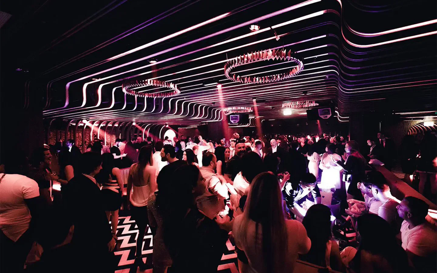 Inside 1 OAK London nightclub, with partygoers and stylish purple neon lighting.