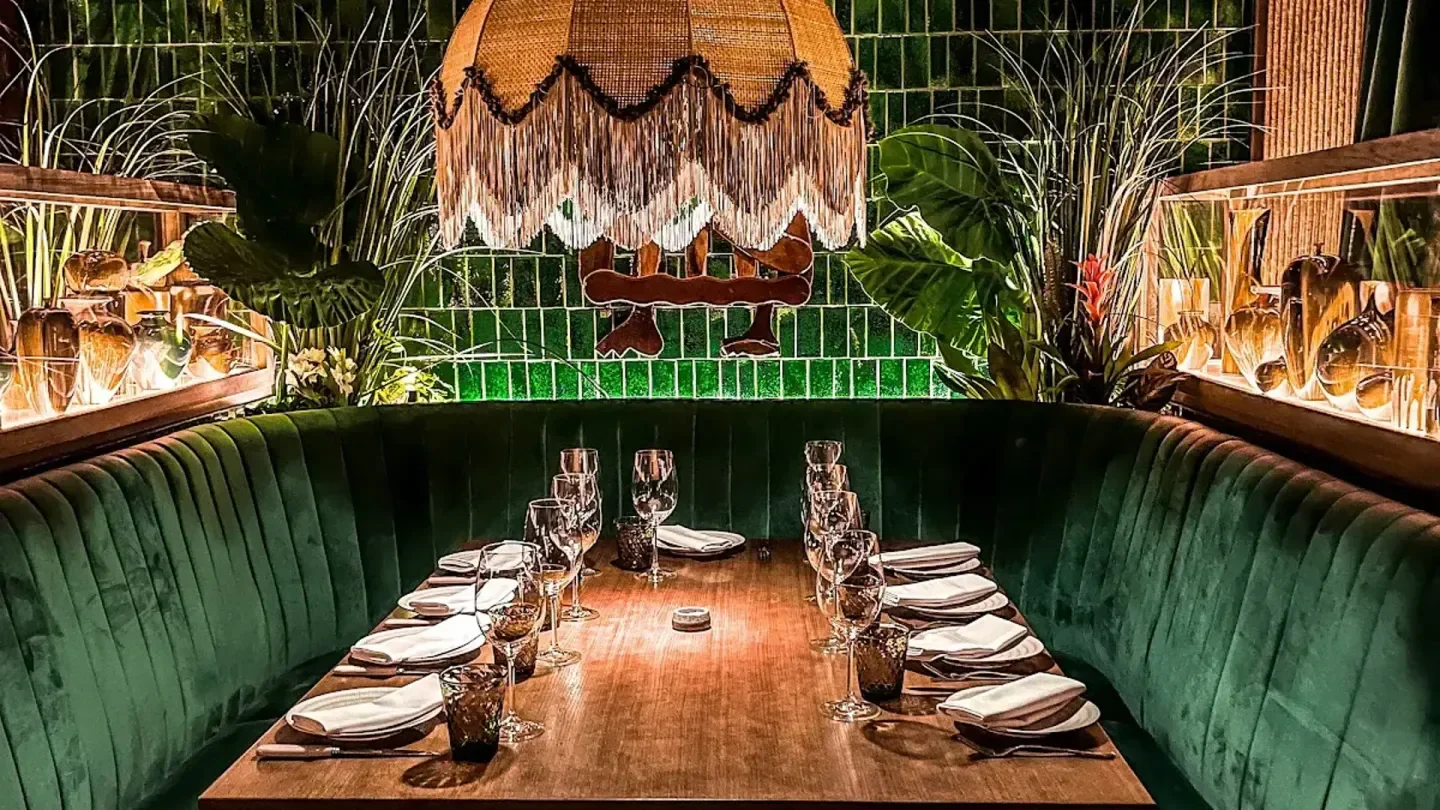 Amazonico London: Stylish dining area with green velvet seating, ready for a meal.