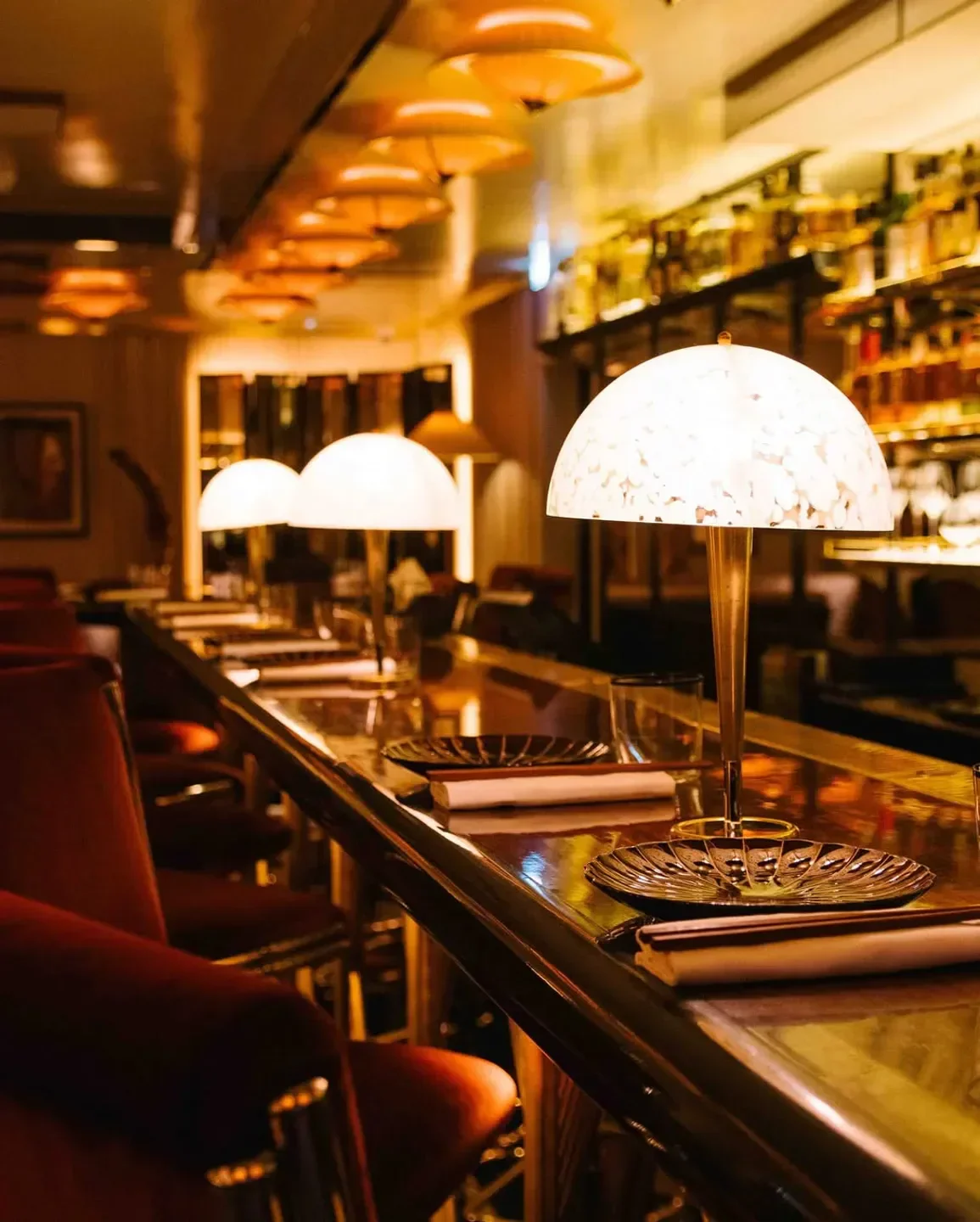 Cozy bar interior at Bar des Prés in London with elegant table lamps and bar stools.