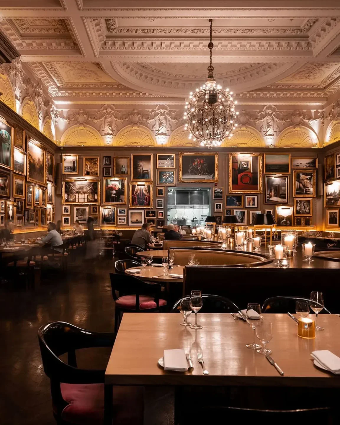 Elegant interior of Berners Tavern restaurant in London, with art-lined walls and chandelier.