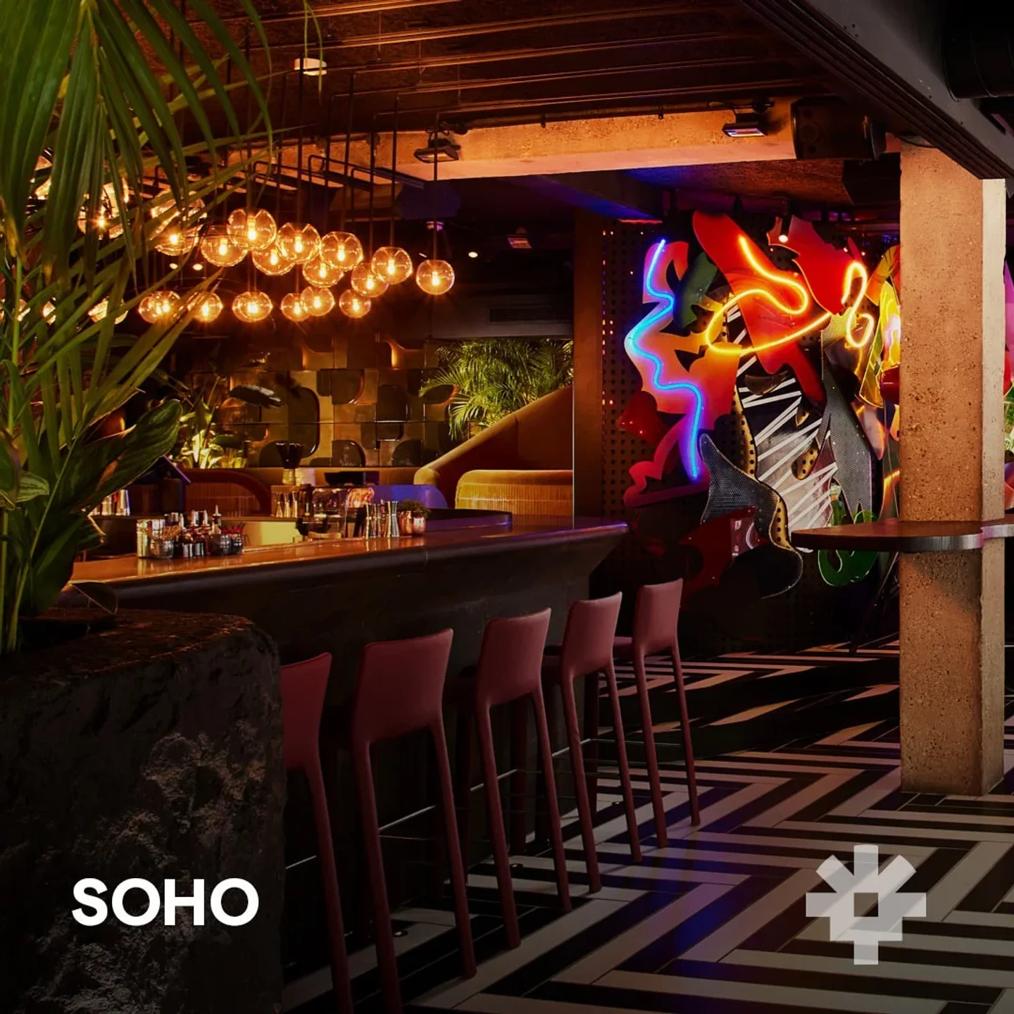 Vibrant neon art decorates the stylish bar interior at Chotto Matte London, featuring plush seating and ambient lighting.