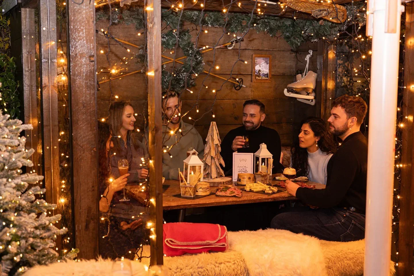 Cozy dining at Coq d'Argent, London, with festive lights and friends around a table.