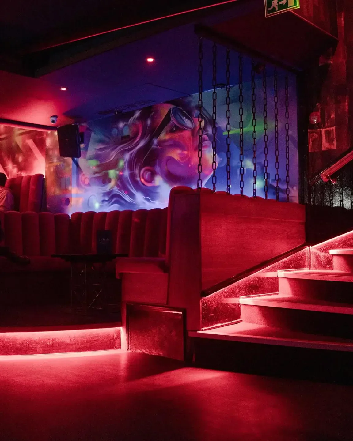 Interior of Dolce Club in London with red lighting and a colorful mural