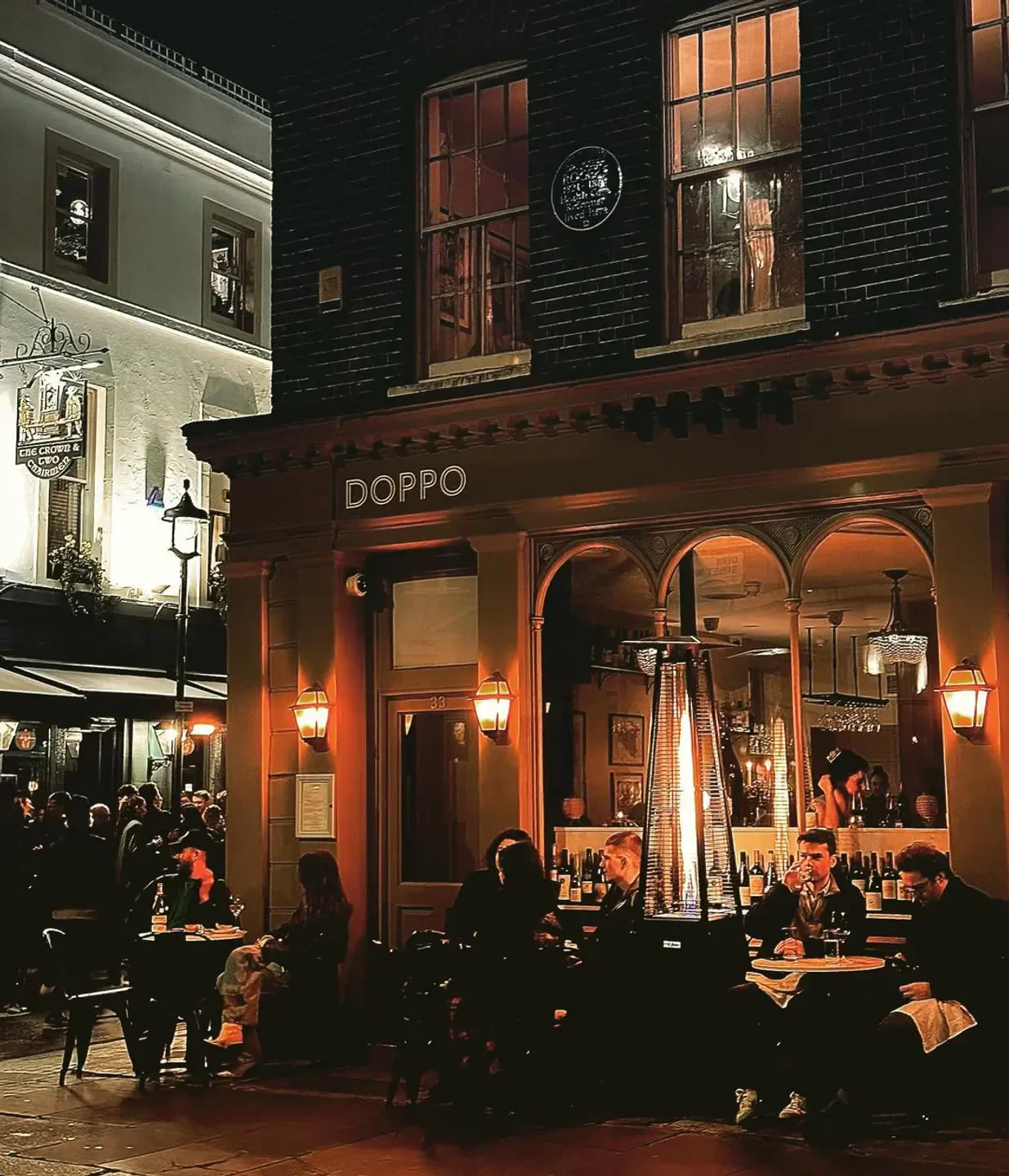 Cozy outdoor seating at Doppo restaurant in London at night, with patrons dining.