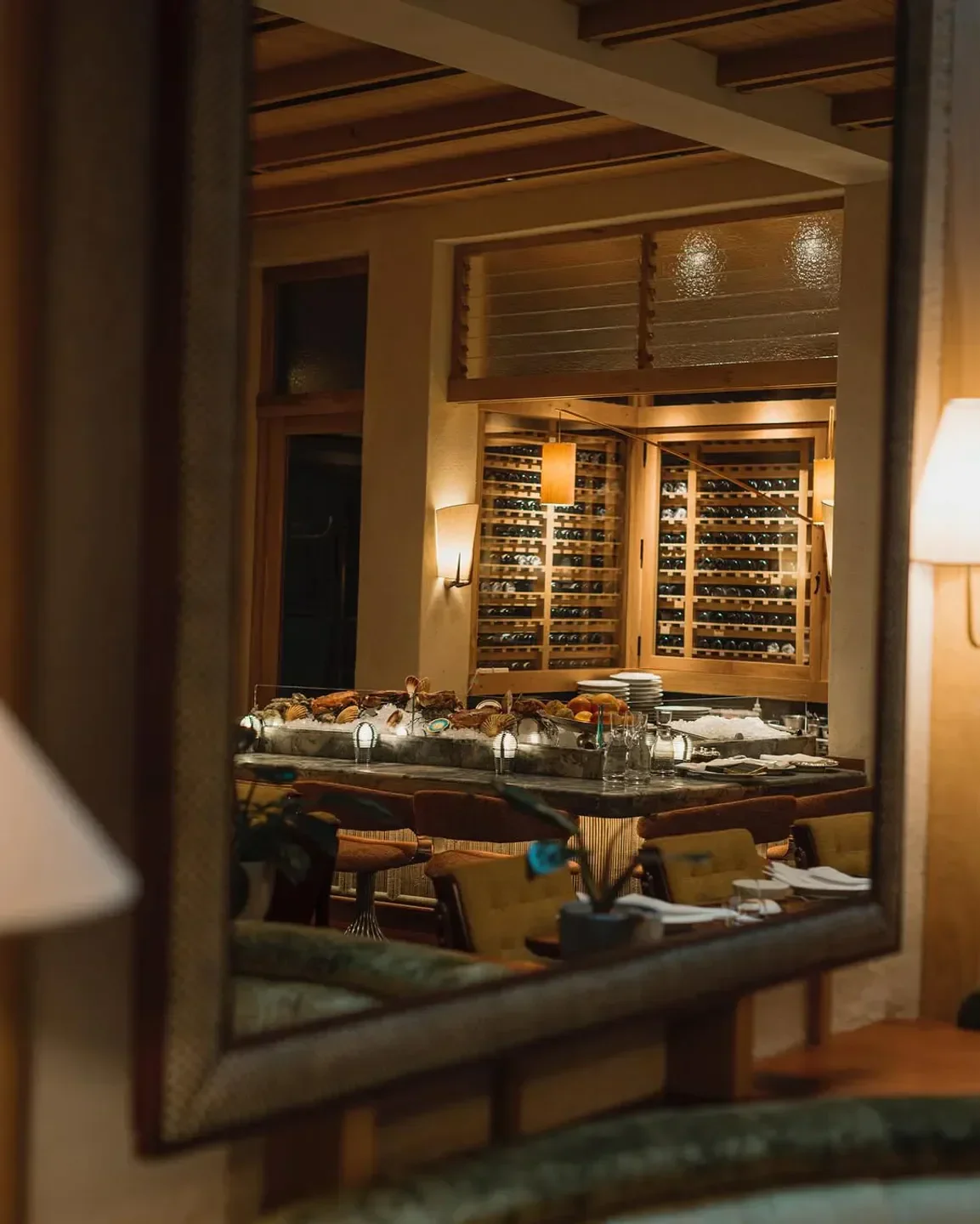 Mirror reflection of the elegant Dovetale restaurant interior in London, showcasing the bar and wine storage.