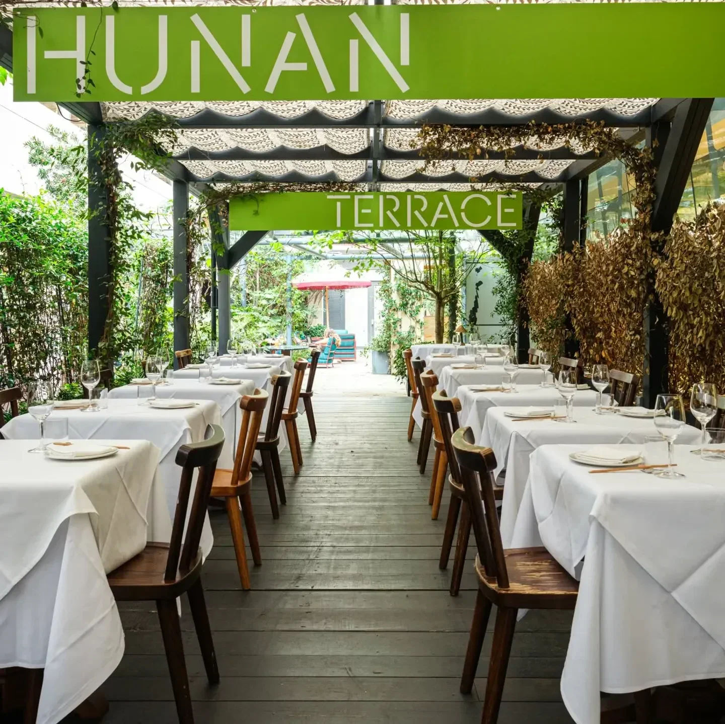 Hunan London restaurant terrace with tables set for dining in a lush, green setting.