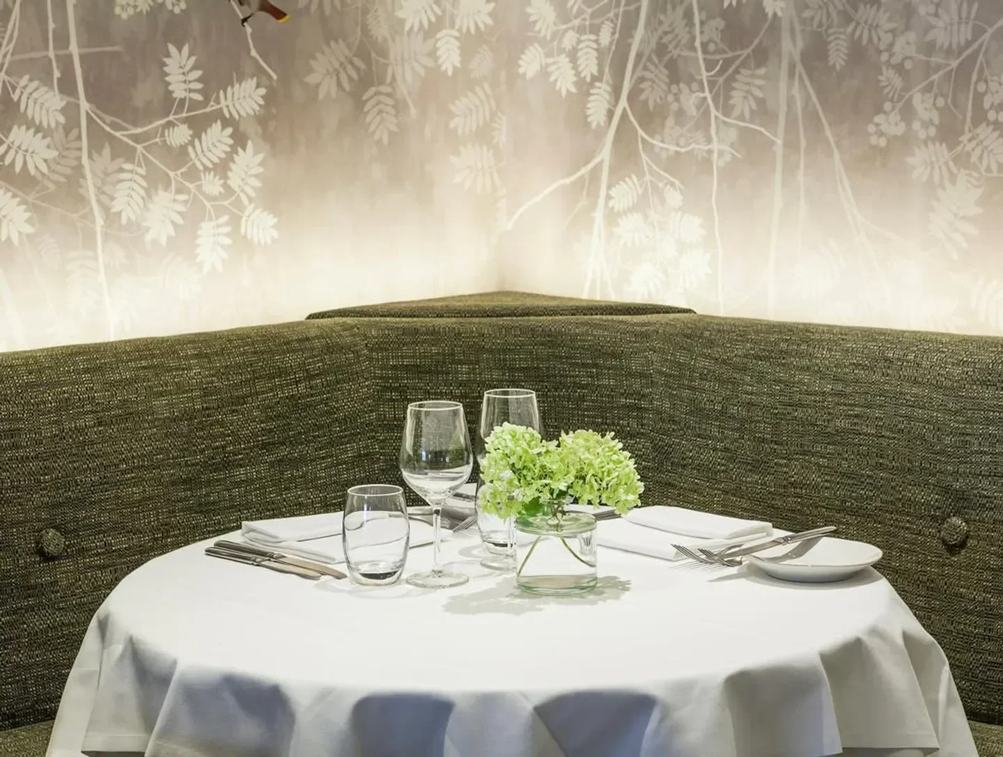 Elegant dining table set at Kitchen W8 restaurant in London, with flower centerpiece and stylish decor