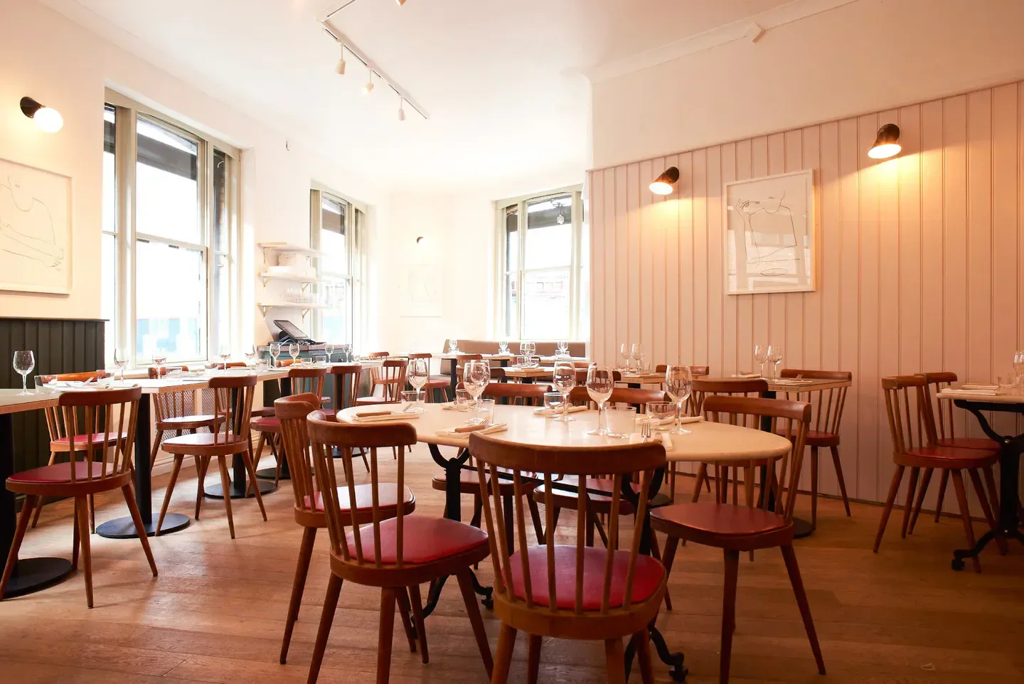 Leroy London restaurant interior, tables set with wine glasses and red chairs, ready for diners.