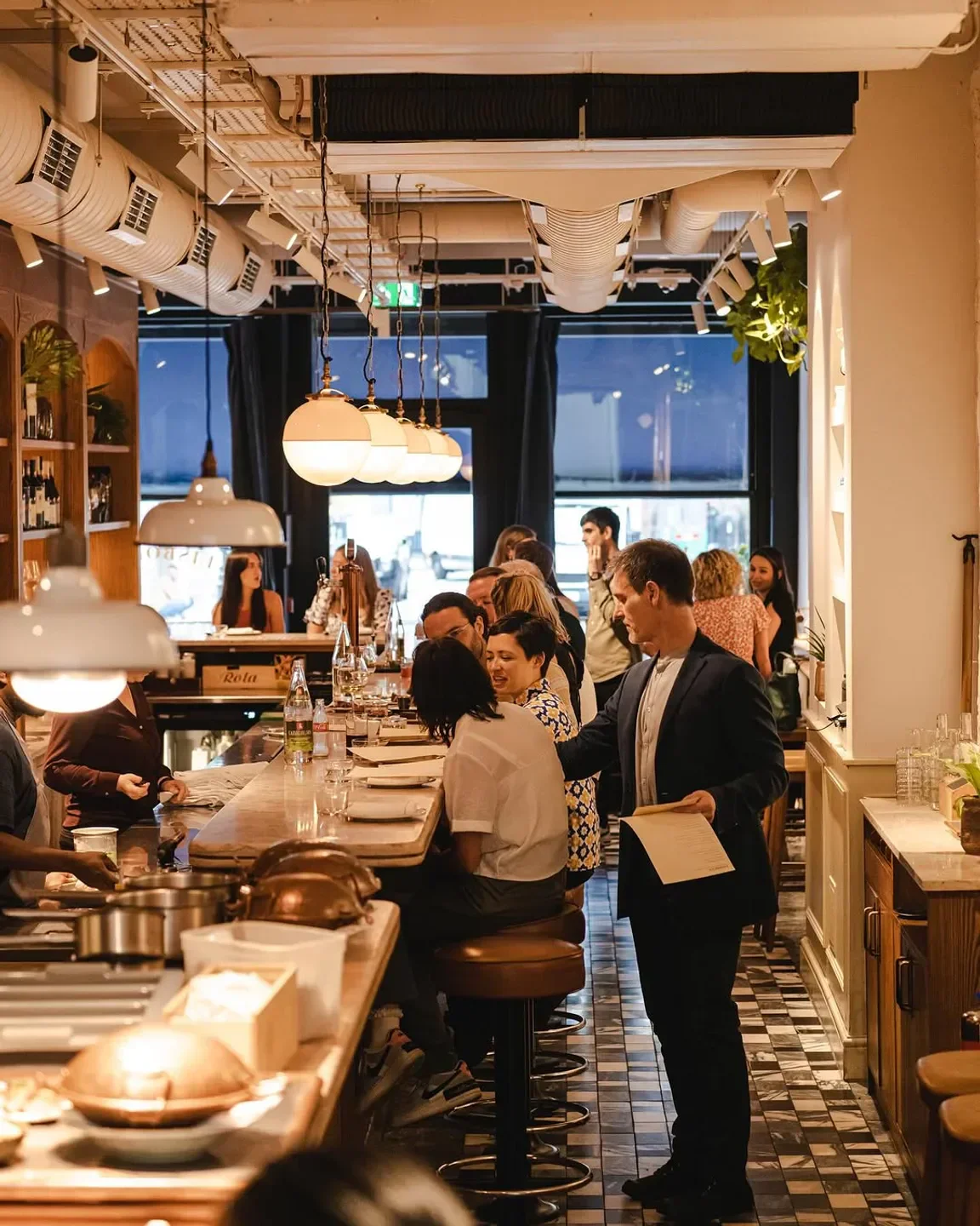 Inside Lisboeta restaurant in London, people enjoying dinner at the bar.