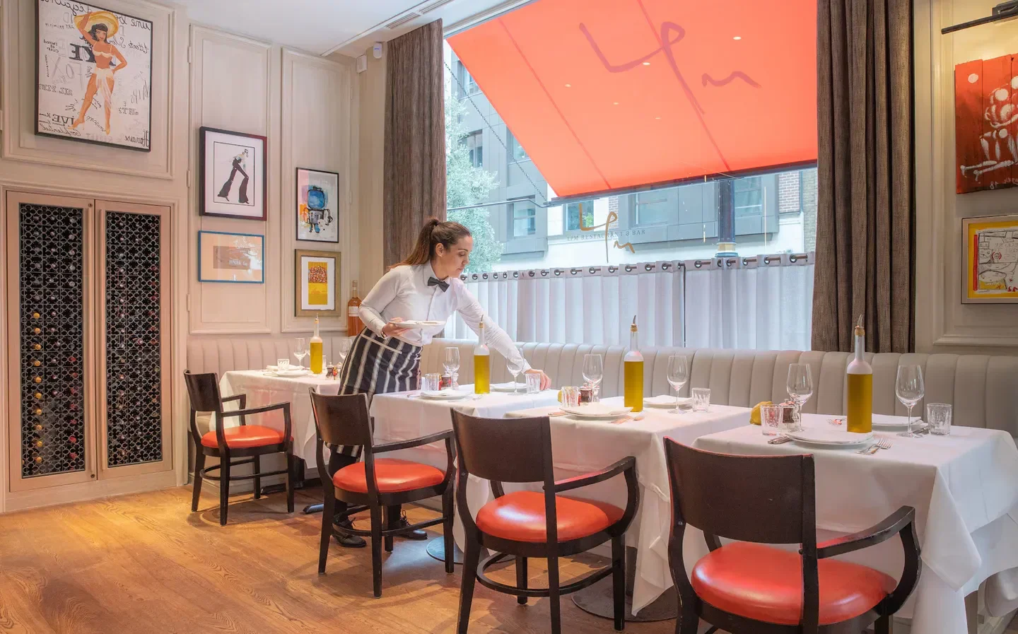 Interior of LPM Restaurant & Bar (La Petite Maison) London, a waiter setting tables.