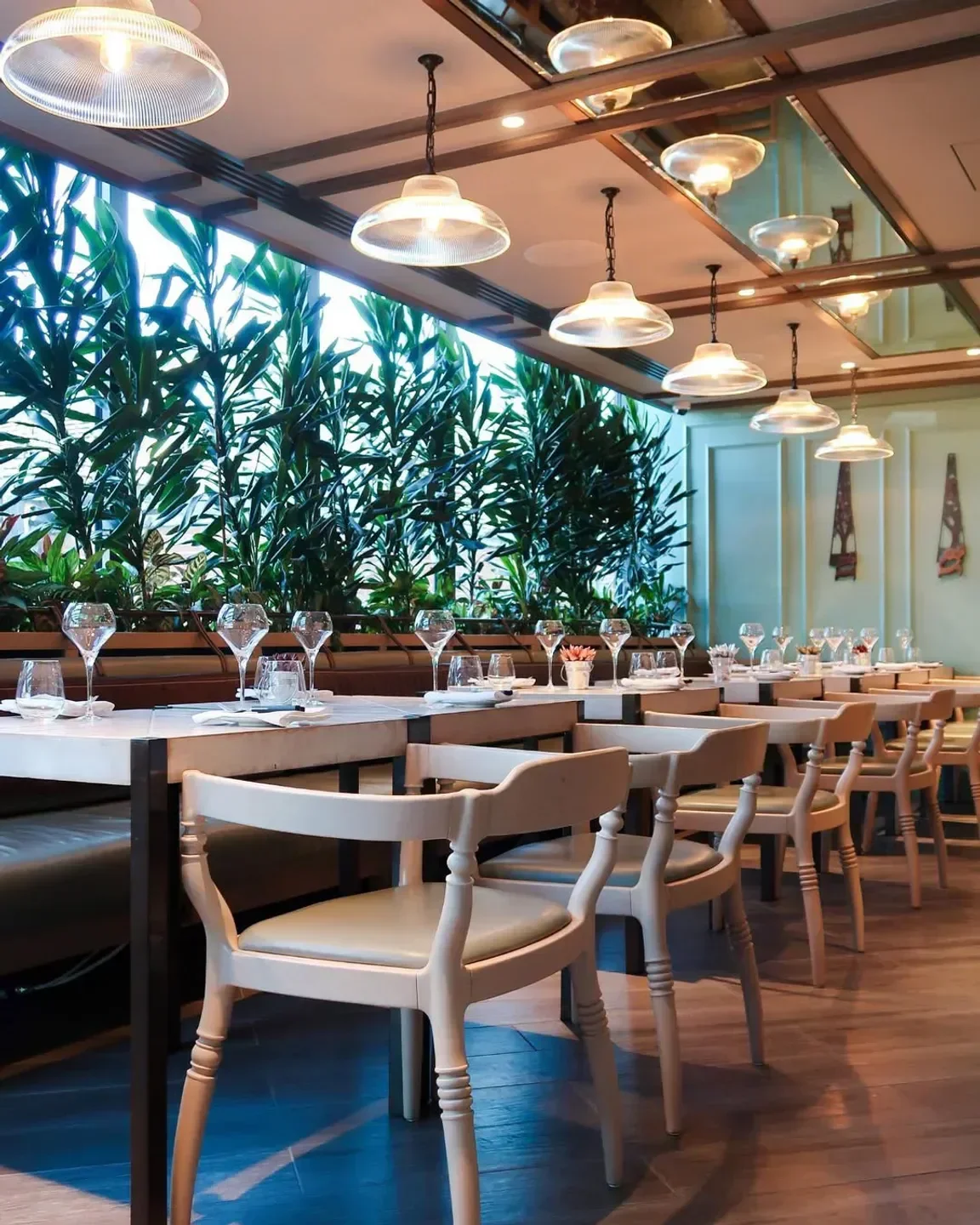 Dining space at Mercer Roof Terrace in London, with lush greenery and elegant chairs.