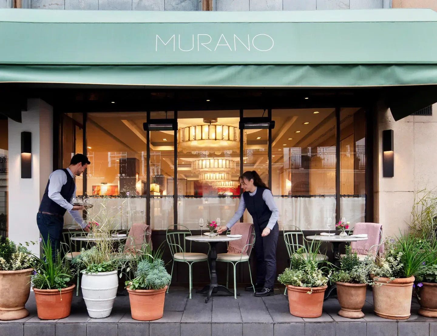 Outdoor seating at Murano restaurant in London, with staff preparing tables.