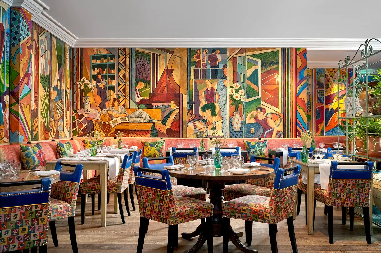 Interior of Oscars Mayfair restaurant in London, featuring vibrant mural and stylish seating.