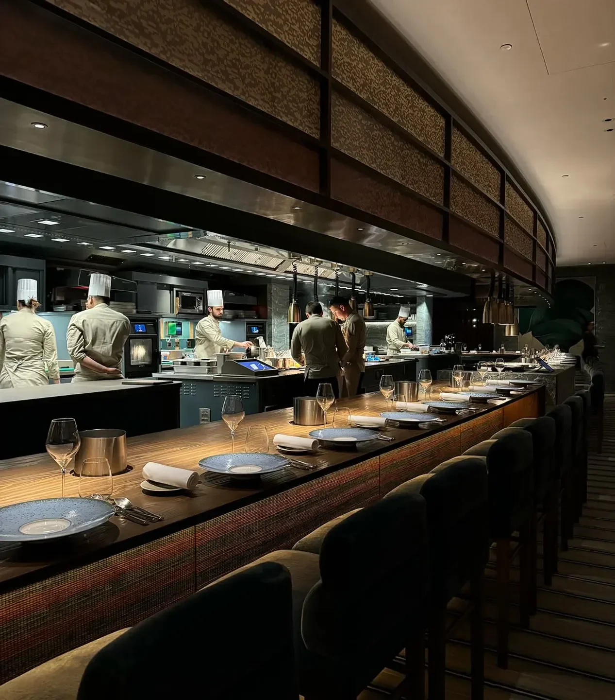 Chefs preparing meals at Pavyllon London restaurant in London, with seating area in foreground.