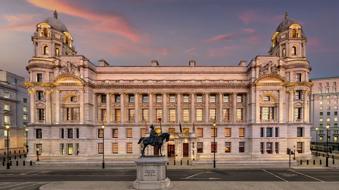 Exterior of Raffles London at The OWO in London at dusk, with a statue.