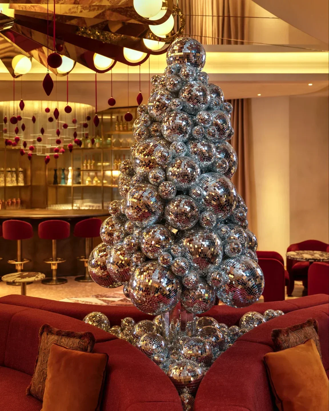 Disco ball Christmas tree inside Revery Bar in London with a red sofa