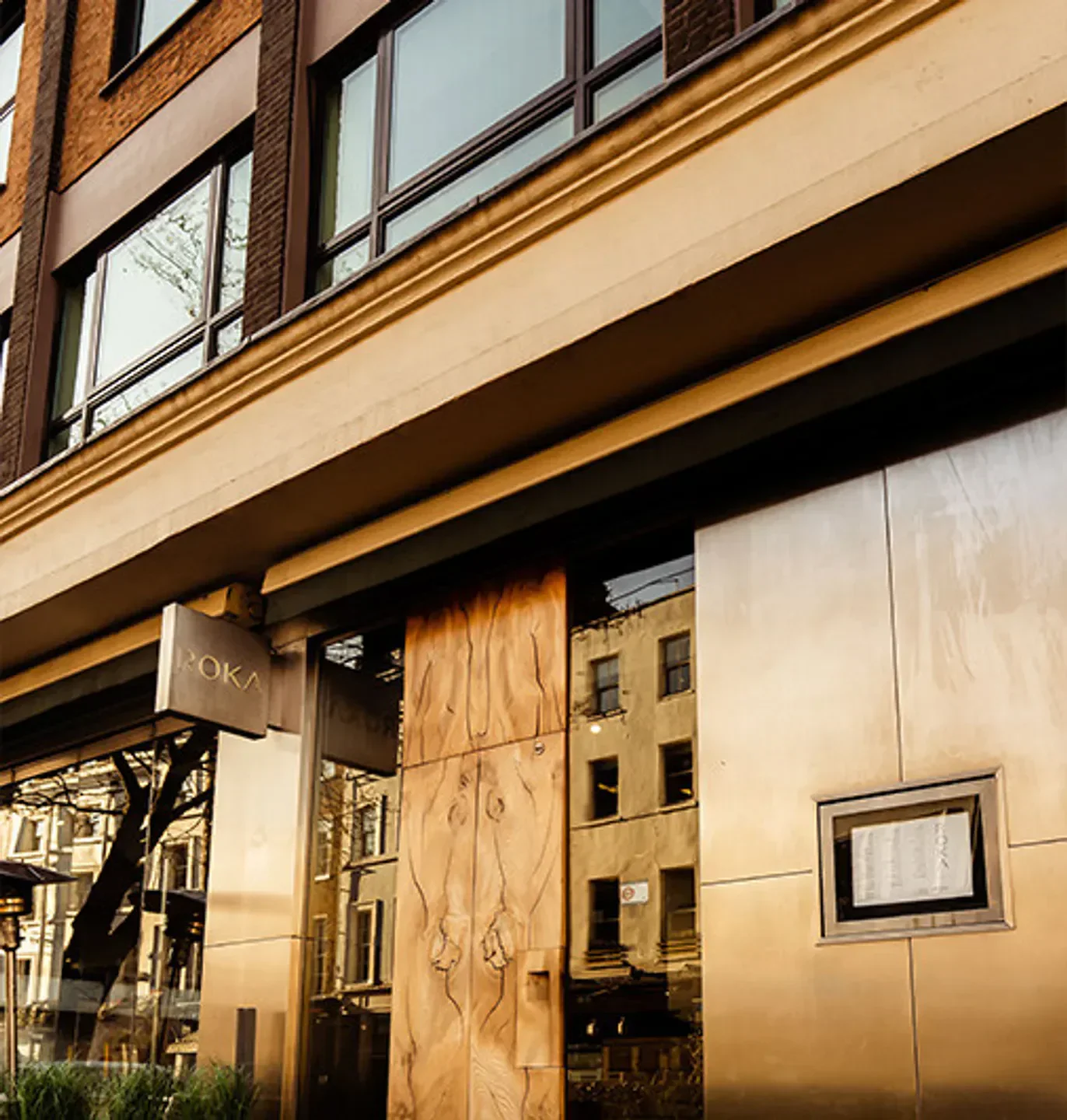 Entrance to ROKA Charlotte Street restaurant in London, with wooden door and sign.