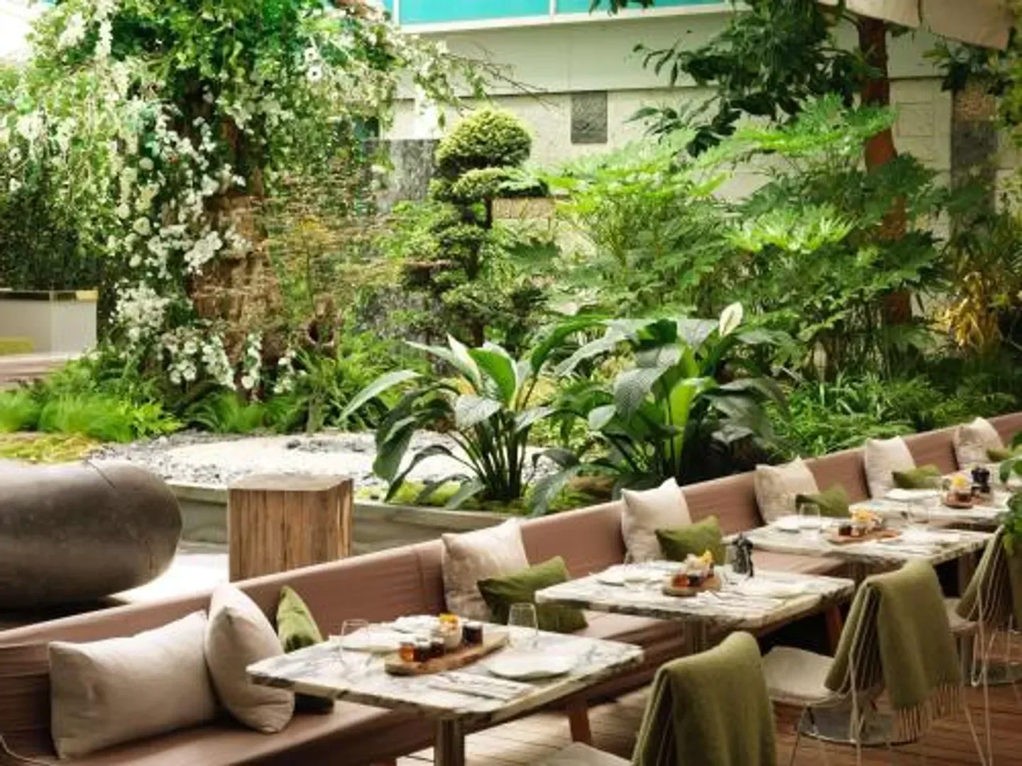 Outdoor dining area at Sanderson restaurant in London, surrounded by lush greenery.