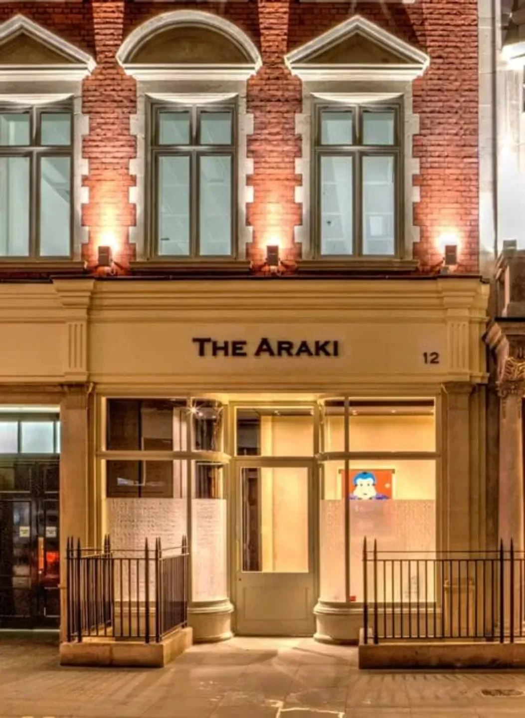 Exterior of The Araki restaurant in London, with a brick facade at night.