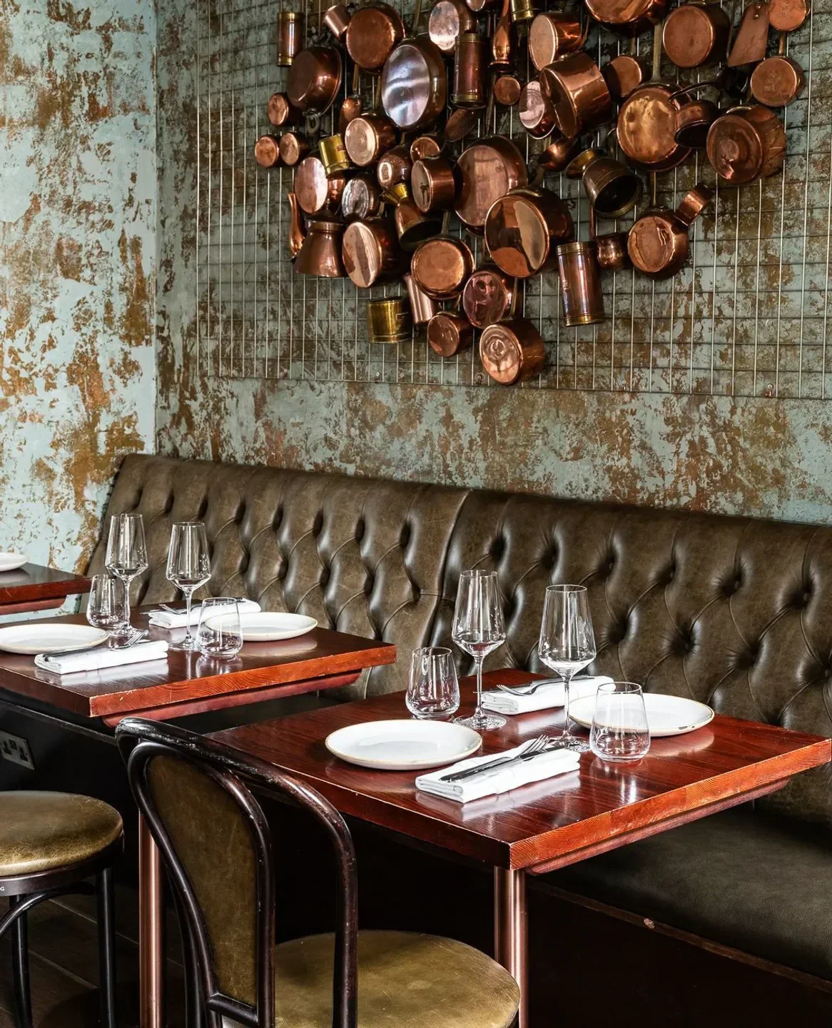 Elegant dining interior at The Ninth in London, featuring copper pot art and tables.
