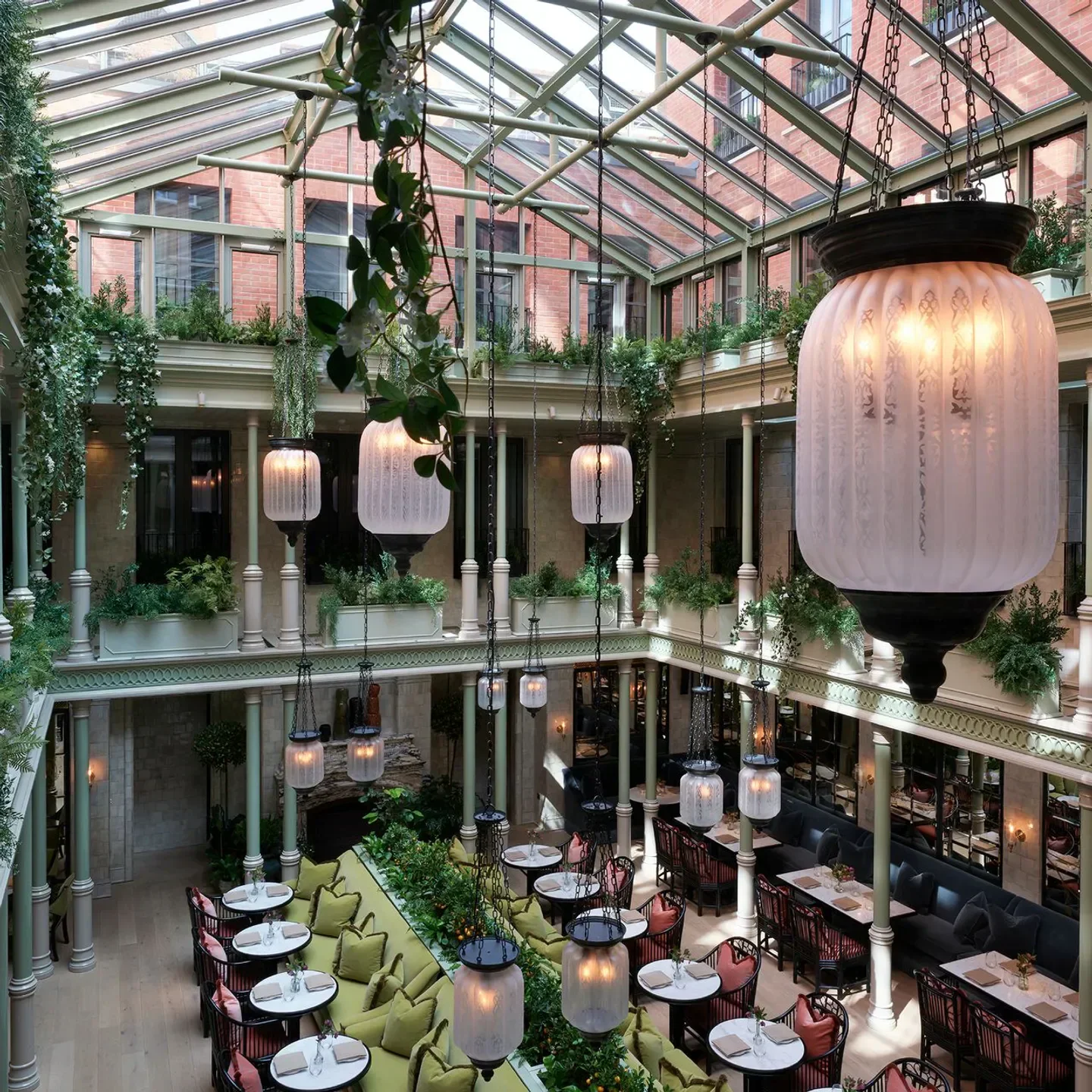 Stunning atrium interior at The NoMad Restaurant in London, with glass ceiling and hanging lanterns.