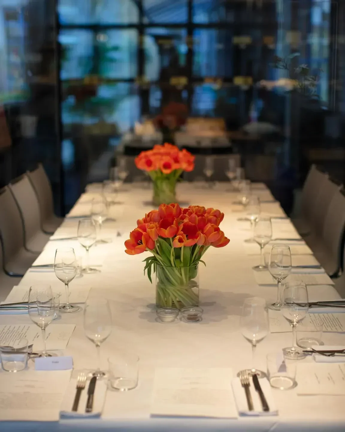 Elegant dining table at The River Café in London, with orange tulips and glassware.