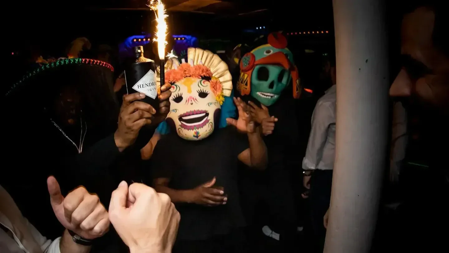 Festive party masks at Tonteria nightclub in London with a bottle and sparkler.