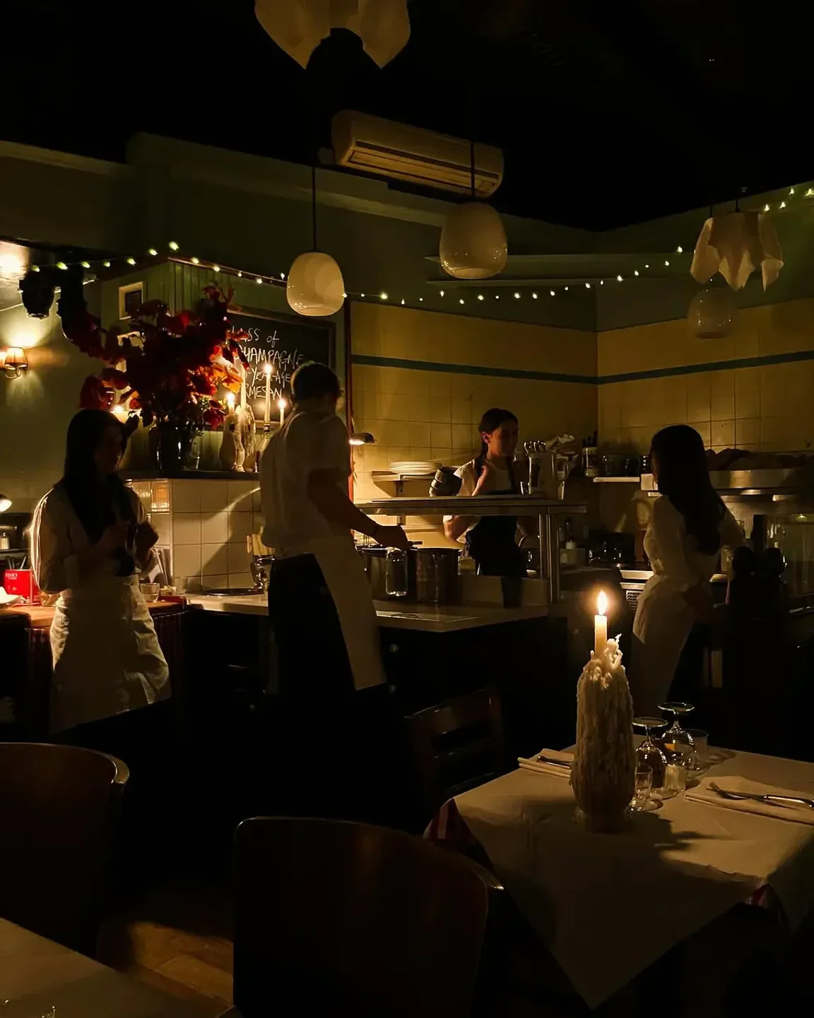 Cozy candlelit interior of Trattoria Brutto in London, with staff preparing food.