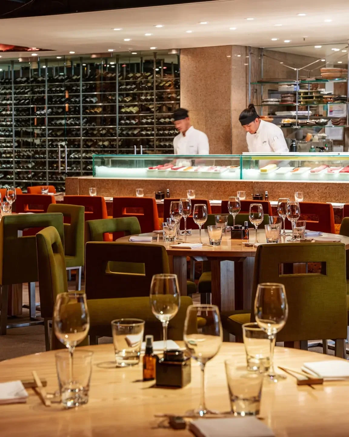 Dining area at Zuma London with chefs in the background preparing food and drinks.